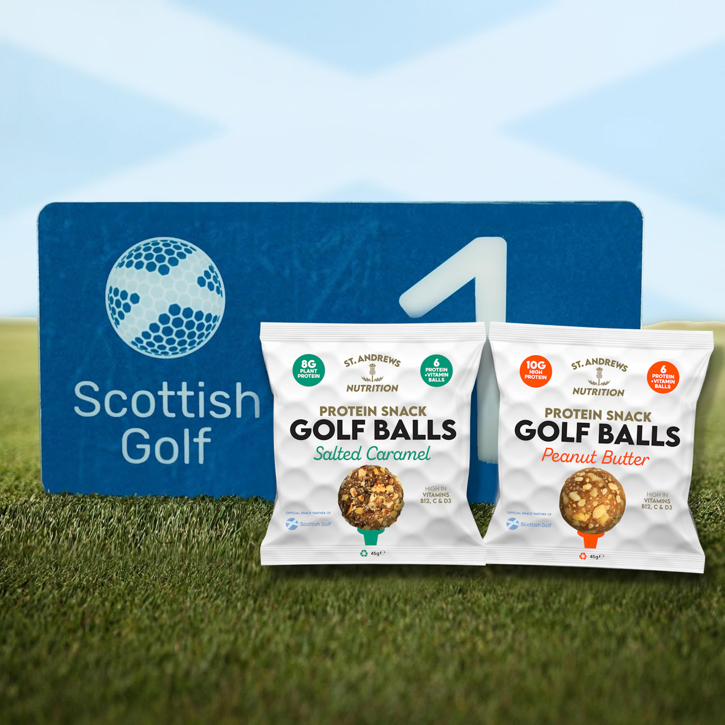 Two packages of St. Andrews Nutrition Protein Snack Golf Balls on grass with a Scottish Golf sign in the background.