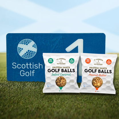 Two packages of St. Andrews Nutrition Protein Snack Golf Balls on grass with a Scottish Golf sign in the background.
